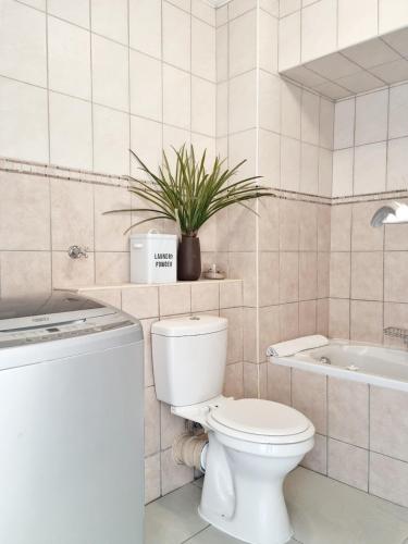 a bathroom with a toilet and a tub and a plant at Island Club by Smart City Stays in Cape Town