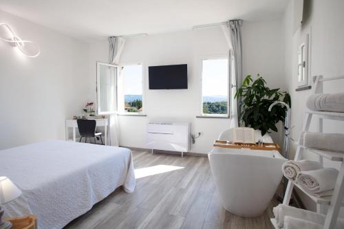 a white bedroom with a bed and a desk at B&B da Baba in Ghizzano