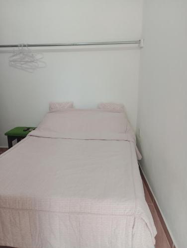 Cama blanca en habitación con pared blanca en Recanto das Videiras, en Maria da Fé