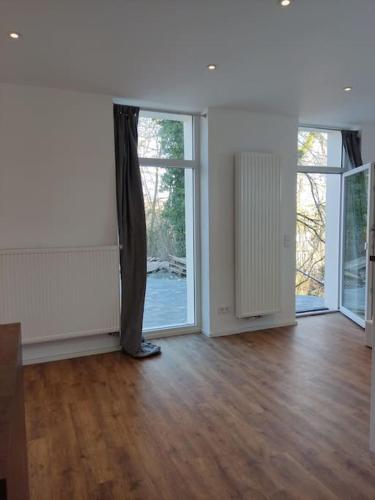 an empty room with wooden floors and large windows at Loft mit großer Terrasse bei der Kinderklinik 2C in Siegen
