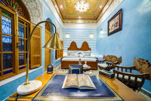 a bedroom with a bed and a desk with a book at Riad Rcif Alif Suite & SPA in Fès