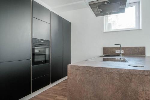 uma cozinha com armários pretos e um lavatório em Loft mit großer Terrasse bei der Kinderklinik 2C em Siegen