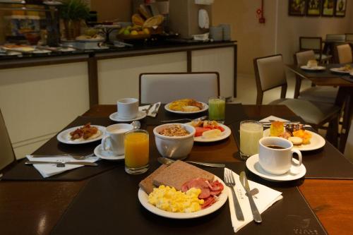 a table with plates of breakfast food on it at Viale Tower Hotel in Foz do Iguaçu