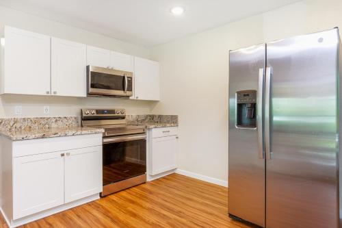a kitchen with white cabinets and a stainless steel refrigerator at Puni Mauka A 31 plus day rental in Pahoa