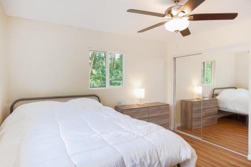 a white bedroom with a bed and a ceiling fan at Puni Mauka A 31 plus day rental in Pahoa
