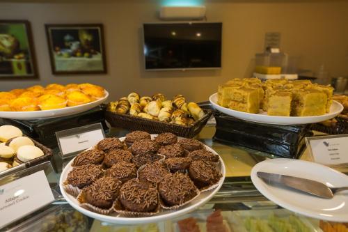 a display case with different types of cakes and pastries at Viale Tower Hotel in Foz do Iguaçu