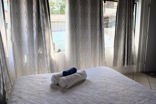 un par de toallas enrolladas en una cama con ventana en Apartamento moderno con vista reserva ecológica, en Búzios