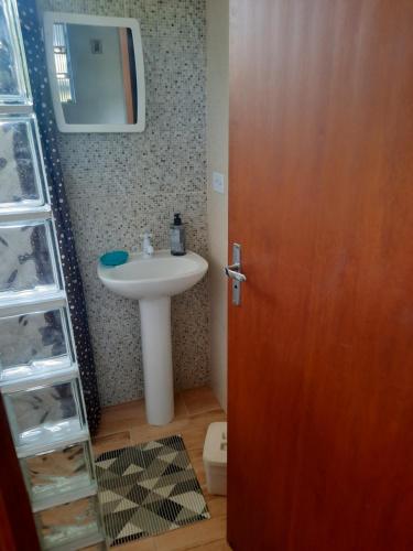 uma casa de banho com um lavatório e uma porta de madeira em Recanto do Estaleiro em Ubatuba