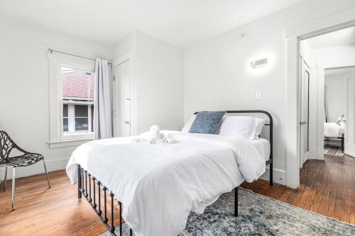 a white bedroom with a large bed and a chair at North End Treasure, beautiful 2 bedroom apartment in Detroit