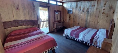 een slaapkamer met 2 bedden in een houten hut bij Cabaña en el Bosque de San José del Pacífico in El Pacífico