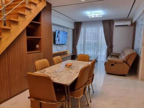 Apartemen Grand Jati Junction Medan 3 Kamar في ميدان: غرفة طعام مع طاولة وكراسي وأريكة