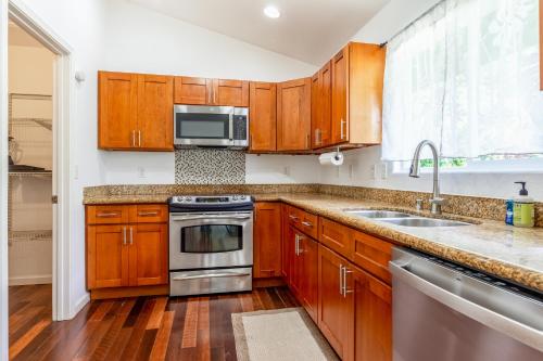 a kitchen with wooden cabinets and stainless steel appliances at Aloha Valley Shores 31 plus day rental in Pahoa