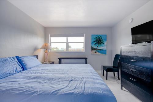 a bedroom with a blue bed and a television at Ocean Reef At Deerfield #4 in Deerfield Beach