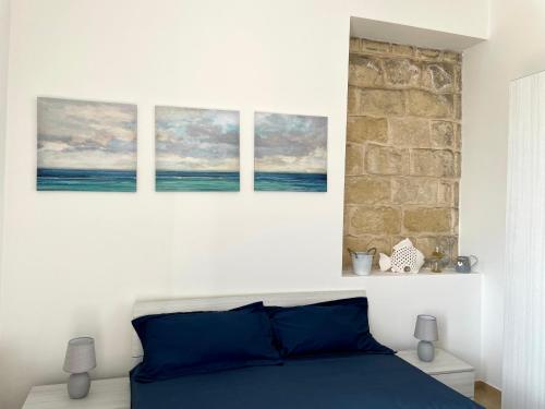 a bedroom with three paintings above a bed at CASA ROSITA-vista cattedrale,mare,tribunale e castello nel pieno CENTRO di Trani-WIFI in Trani