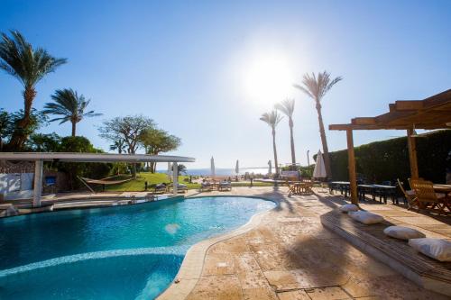 a swimming pool with palm trees and a view of the ocean at Ras Katy Sunset Views in Sharm El Sheikh