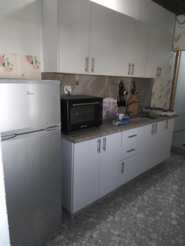 a kitchen with white cabinets and a microwave and a refrigerator at Moon light in Jerusalem