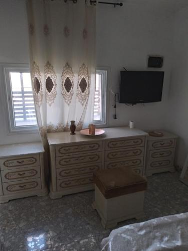 a bedroom with a dresser and a tv and a bed at Moon light in Jerusalem