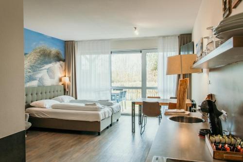 a bedroom with a bed and a desk and a table at Hotel De Zeeuwse Kust (family only) in Renesse