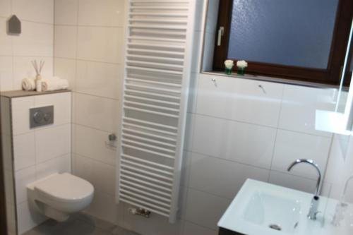een witte badkamer met een toilet en een wastafel bij Ferienhaus Blumenhain - Wohnung "Kirchblick" in Bad Wünnenberg
