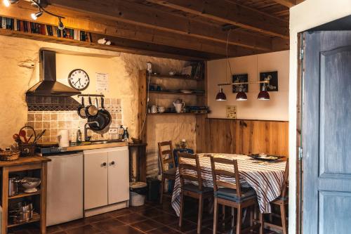 a kitchen with a table and chairs and a clock at Hof Mellon in Plouguernével