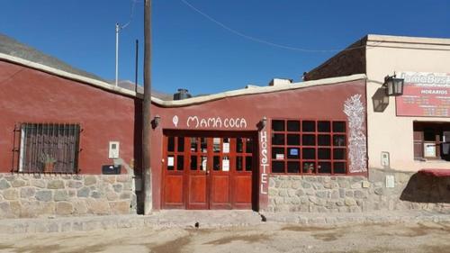 un bâtiment en briques avec une porte rouge dans une rue dans l'établissement Hostal Mamacoca, à Purmamarca