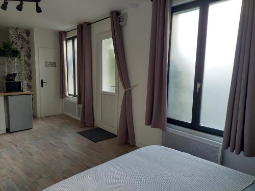 a bedroom with a bed and a door with windows at Charmant Studio au calme 