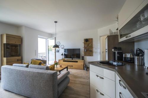 uma cozinha e sala de estar com um sofá e uma mesa em Ferienwohnung Tor zum Meer - Neubau mit Sauna, Fahrstuhl und Tiefgarage em Kühlungsborn