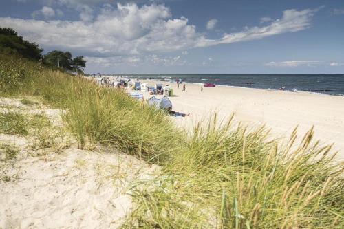 a group of people on a beach with the ocean at Ferienwohnung Tor zum Meer - Neubau mit Sauna, Fahrstuhl und Tiefgarage in Kühlungsborn