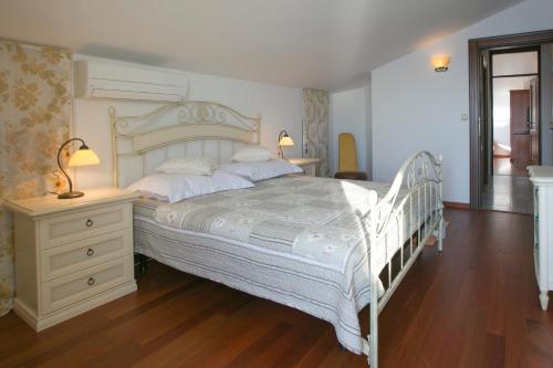 a bedroom with a white bed and a dresser and lamp at Royal Holiday Apartments Sveti Stefan in Sveti Stefan