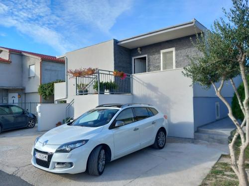 a white car parked in front of a house at Apartman Marita in Kaštela