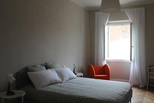 a bedroom with a bed and an orange chair and a window at Castruccio 4 - casa con vista sulla via Francigena in Fucecchio