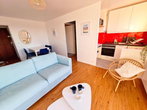 ein Wohnzimmer mit einem blauen Sofa und einem Tisch in der Unterkunft Superbe appartement vue mer 180° (wifi + parking) in Villers-sur-Mer