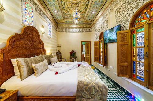 a bedroom with a large bed and stained glass windows at Riad Rcif Alif Suite & SPA in Fès