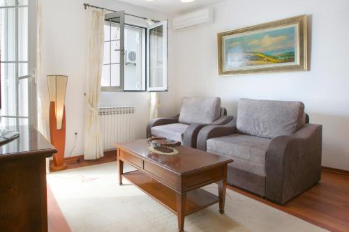 a living room with a couch and a chair and a table at Royal Holiday Apartments Sveti Stefan in Sveti Stefan