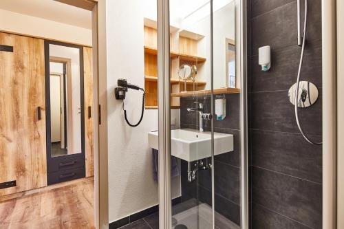 ein Bad mit einem Waschbecken und einer Dusche in der Unterkunft Das Reiners in Grafenau