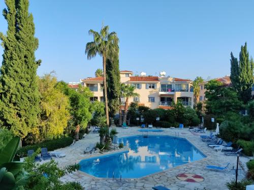 a view of a resort with a swimming pool and palm trees at Rachel suite by the pool Paphos in Paphos City