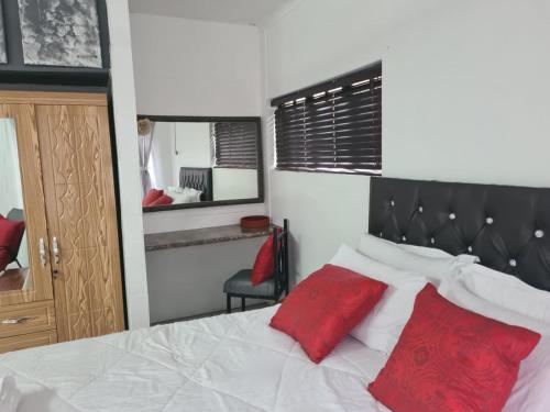 a bedroom with a bed with two red pillows at Chantelle's Overnight Room in Richards Bay