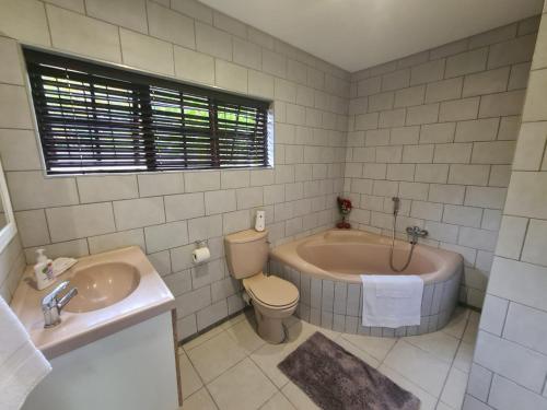 a bathroom with a tub and a toilet and a sink at Chantelle's Overnight Room in Richards Bay