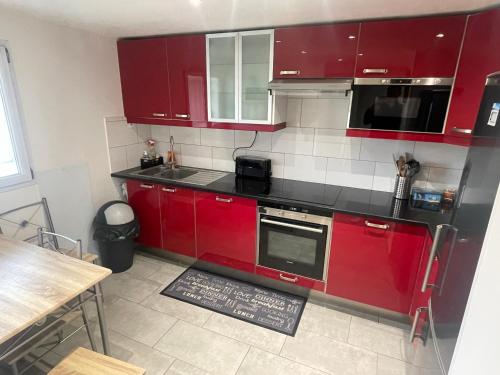 une cuisine avec des armoires rouges et un comptoir dans l'établissement Maison Hotel proche Paris et Orly, à Athis-Mons