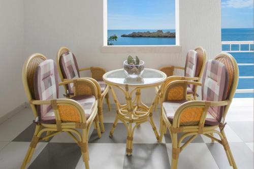 a dining room with a table and four chairs at Royal Holiday Apartments Sveti Stefan in Sveti Stefan