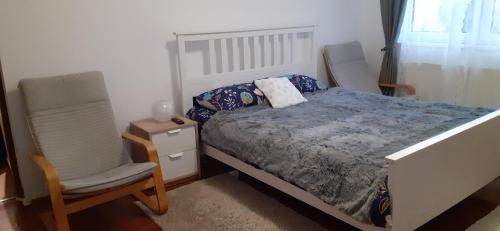 a bedroom with a bed and a chair at Apartament 2 cam Predeal in Predeal
