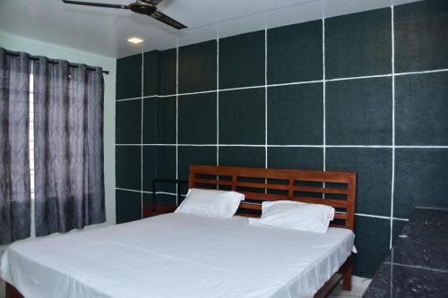 een slaapkamer met een bed en een groene betegelde muur bij CHANDRA ROYAL RESIDENCY in Vellore
