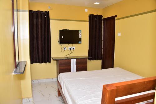 a bedroom with a bed and a tv on the wall at CHANDRA ROYAL RESIDENCY in Vellore