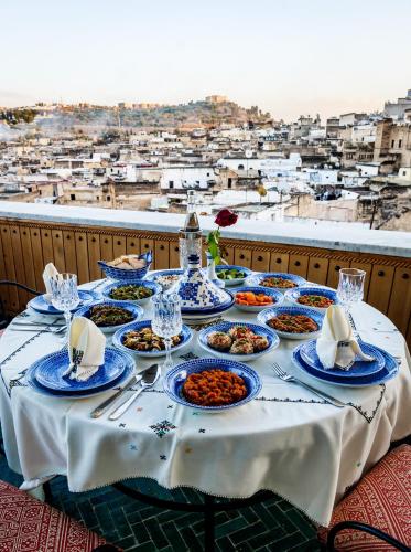 a table with plates of food on a balcony at Riad Rcif Alif Suite & SPA in Fès