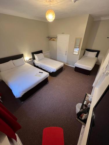 a hotel room with two beds and a red chair at Lost Guest House Peterhead in Peterhead