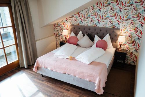 a bedroom with a large bed with red pillows at Landhotel Lindenhof in Feld am See