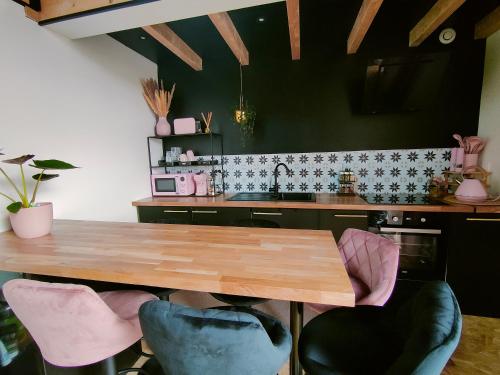 eine Küche mit einem Holztisch und rosa Stühlen in der Unterkunft Dans les étoiles in Cuttura