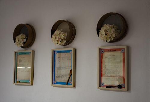 een muur met vier ingelijste certificaten en bloemen erop bij À dos Reis in Faro