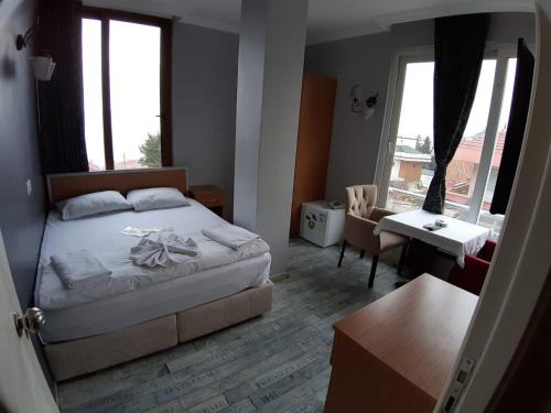 a bedroom with a bed and a desk and windows at ZEMAHOTEL in Büyükçekmece