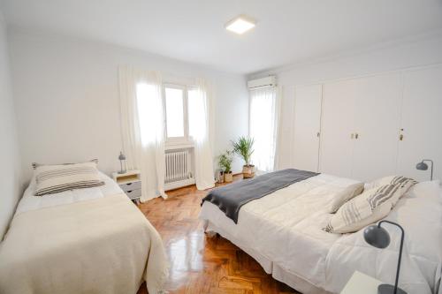 2 camas en un dormitorio con paredes blancas y suelo de madera en Anden Espejo en Mendoza